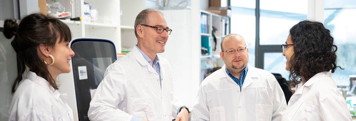 George in his lab, chatting with members of his former Ludwig Lausanne team, Ioanna Rota (left), Jesus Corria and Laura Cabizzosu (right).